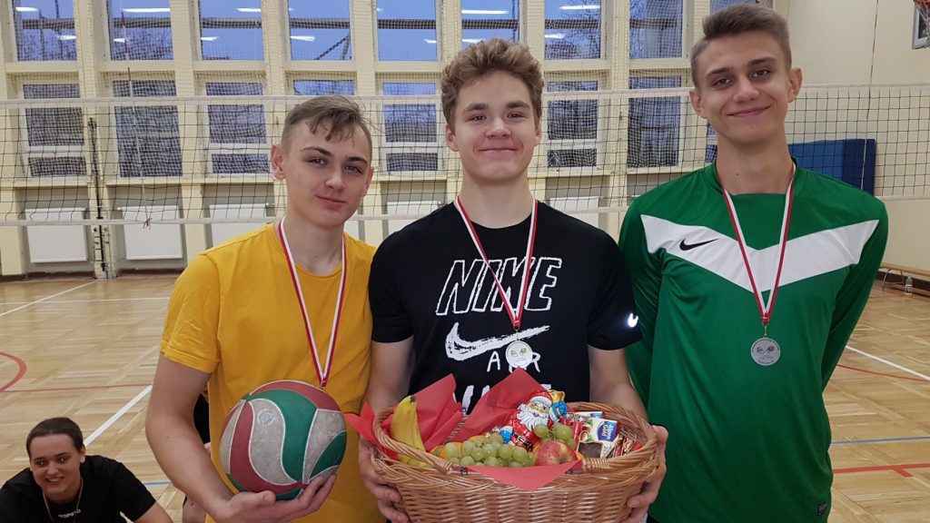 Trzech uczniów z medalami i koszykiem nagród
